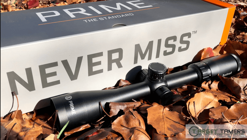 Bushnell Prime rifle scope sitting in a pile of leaves next to its packaging